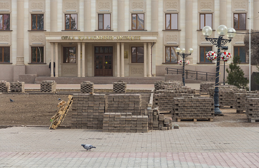 Uralsk, Oral, Kazakhstan (Qazaqstan), 24.03.2020 - Replacement of paving stones with new ones on Abai Square in the city of Uralsk. Disassembled paving stones stacked on pallets. City Akimat building.