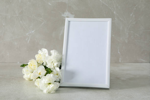 istock A photo frame with white flowers nearby, on the table 2148827570