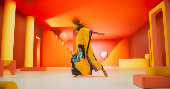 Beautiful Black Woman in African Outfit Dancing Energetically in Geometric Abstract Orange Environment. Creative Female Performing Dance Choreography in Studio, Making Moves, Having Fun.