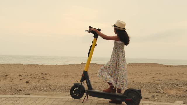 A girl is riding a scooter on a beach. Summer concept