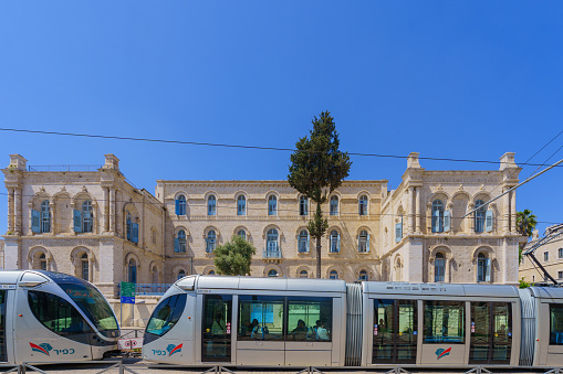 Jerusalem, Israel - April 12, 2024: View of the St. Louis French Hospital building, and a light train passing, near the old city of Jerusalem, Israel