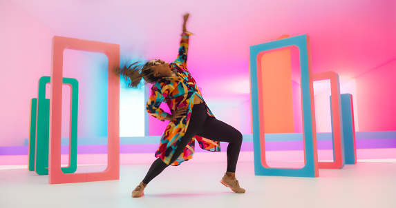Colorful Geometric Abstract Aesthetic: Portrait of Black Woman Happily Dancing to Energetic Music in a Studio. Lively African Female Dancer Celebrating Life, Expressing Herself Through Movement.