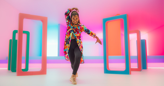 Portrait of a Talented Black Female Artist Showcasing Graceful Movements and Expressive Joyful Emotions with Her Innovative And Energetic Modern Dance Routine in a Colorful Neon Lit Studio.