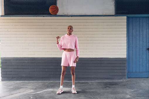 Basketball player portrait against a brick wall in a basketball court.