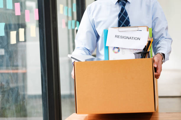 istock Man leaves office holding a box with personal items, including resignation letter. 2148831690