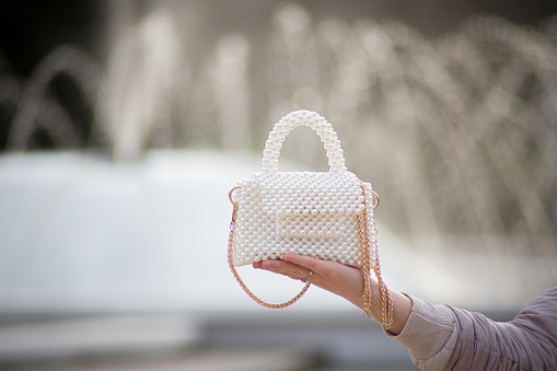 Woman hands holding fashionable and elegant pearl beaded white purse