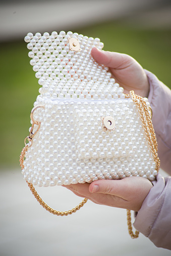 Woman hands and opening holding fashionable and elegant pearl beaded white purse