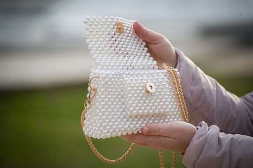 Woman hands and opening holding fashionable and elegant pearl beaded white purse