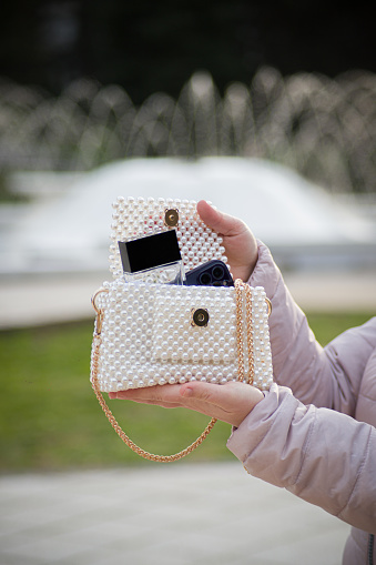 Woman hands holding fashionable and elegant pearl beaded white purse