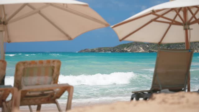 View to the opposite rocky coast from the sun loungers under beach umbrellas. Rest and relaxation summer holiday scene