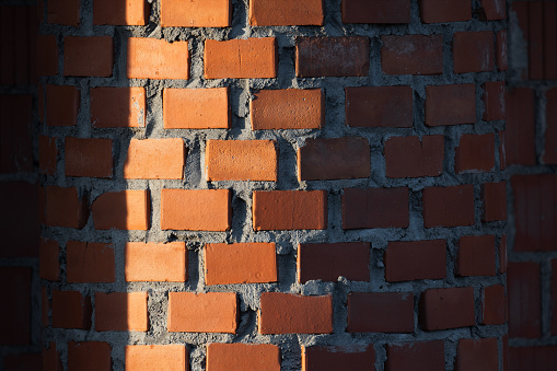 Red round brick wall pattern with deep shadows. Abstract photo background with selective focus