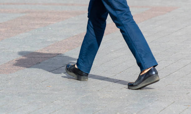 Legs of a man walking on paving slabs.
