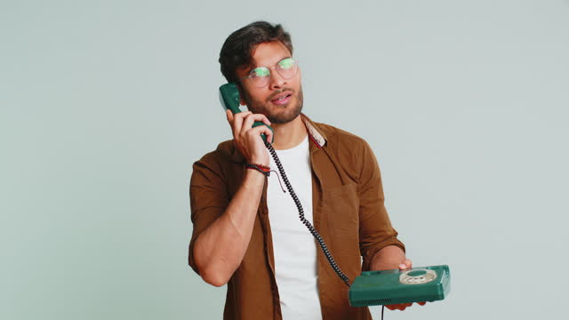 Indian man talking on wired landline vintage telephone, advertising proposition of conversation