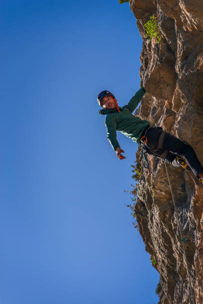 istock Caucasian man with black hair. Practicing rock climbing. Hanging by one hand and looking into the distance. 2148836473