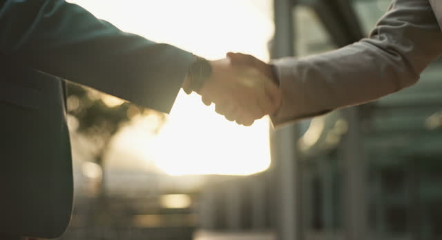 Business people, sunset and handshake for agreement in city, networking and introduction outdoors. Professionals, dusk and welcome in recruitment or communication, closeup and hire for collaboration