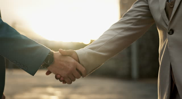 Business people, sunset and handshake for partnership in city, networking and introduction outdoors. Professionals, dusk and welcome in recruitment or integration, closeup and hire for collaboration