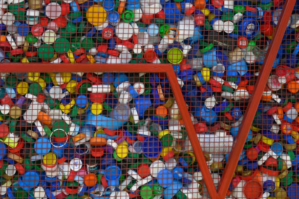 Container for collecting plastic bottle caps. Collection of plastic caps for recycling materials. Many multicolored single use plastic bottle caps. Recycling of secondary raw materials. Environmental protection. contenedor para recoger tapones de botellas de plástico. recogida de tapones de plástico para materiales reciclados. muchas tapas de botellas de plástico multicolores de un solo uso. reciclaje de materias primas secundarias. protección del medio ambien