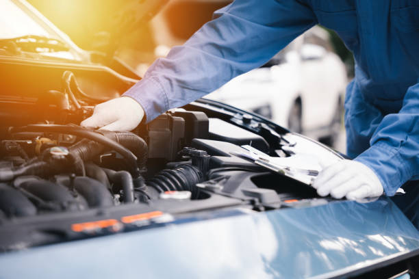 istock Auto mechanic writing on a clipboard checking car engine at workshop. Expertise in car service and repair technology-driven. Technician ensuring safety smiling at the challenge. 2148837005