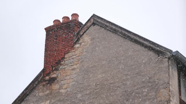 Snowflakes Descending on a Brick Chimney and Stone Building