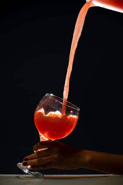 Pouring berry syrup  into water glass on white background