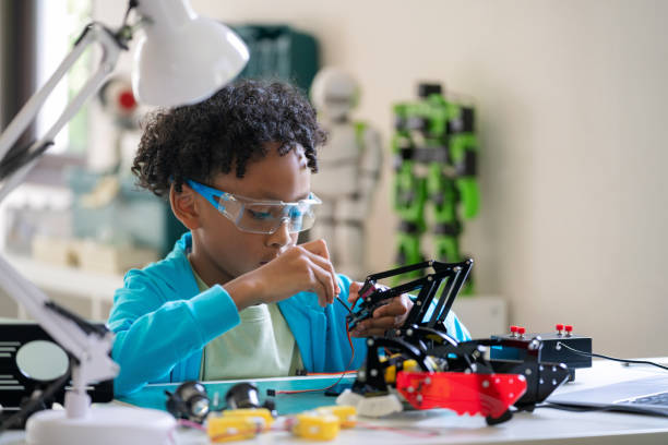 istock An African pre-adolescent boy is using a screwdriver to tighten the nuts on a mechanical arm, demonstrating his hands-on approach to learning and innovation. He is focused and concentrated, working on a school science project to improve the efficiency 2148839994
