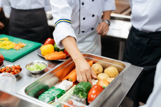 Chefs cooking and picking a fresh vegetables from tray on the table in kitchen