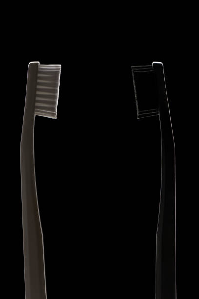 cepillos de dientes blancos y negros sobre fondo negro - dental hygiene elegance black toothbrush fotografías e imágenes de stock