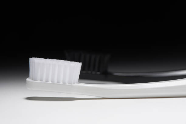 white and black toothbrushes on dramatic background - dental hygiene elegance black toothbrush stock-fotos und bilder