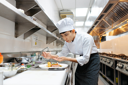 Young Asian Chinese chef decoration and plating dish before serving