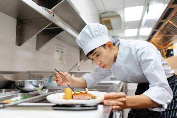 Young chef plating gourmet dish in kitchen