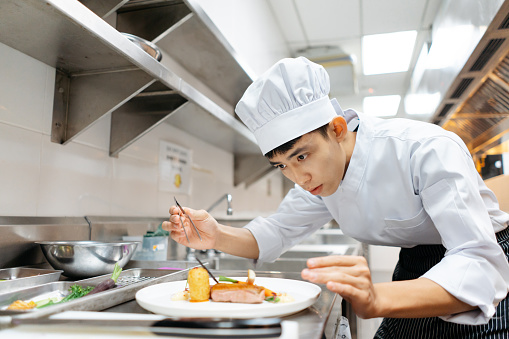 Young Asian Chinese chef decoration and plating dish before serving