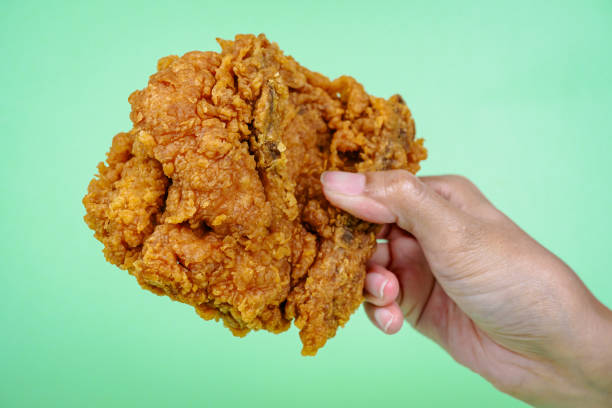 istock Female hand holding fried chicken on green background. 2148843554