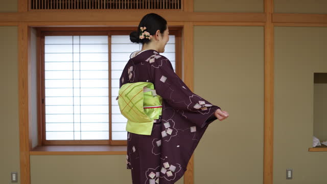 Portrait of female tourist wearing kimono in Japanese tatami room - turning around