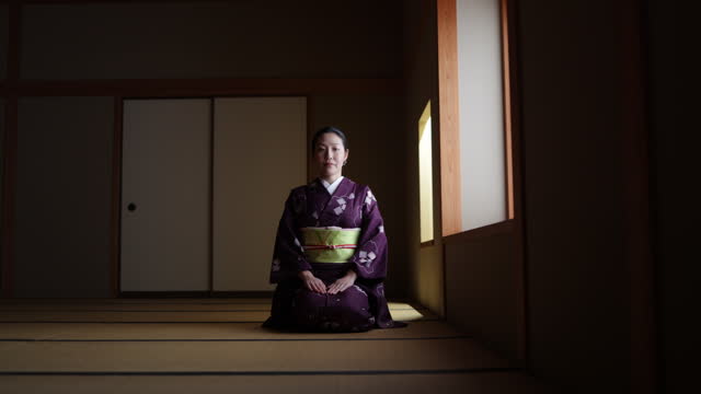 Female tourist in purple kimono sitting on heels in dark Japanese tatami room and bowing - slow motion - part 3 of 4