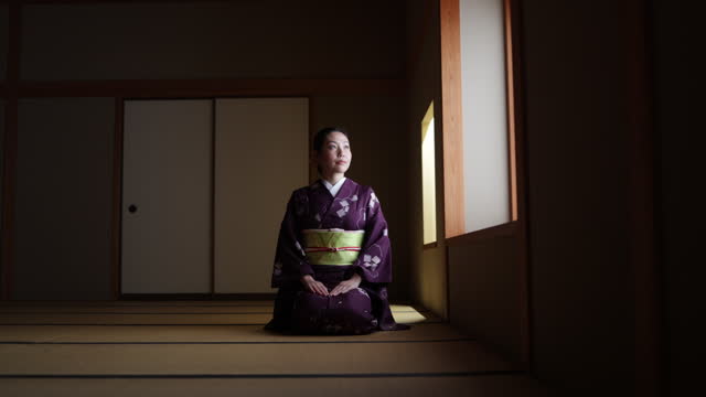 Female tourist in purple kimono sitting on heels in dark Japanese tatami room and bowing - slow motion - part 4 of 4