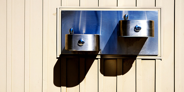 Steel drinking fountain mounted on wall for public use