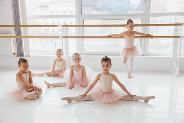 istock Children, girls in pink ballet skirts practicing stretching exercises at modern dance studio. Classical ballet school. 2148846165