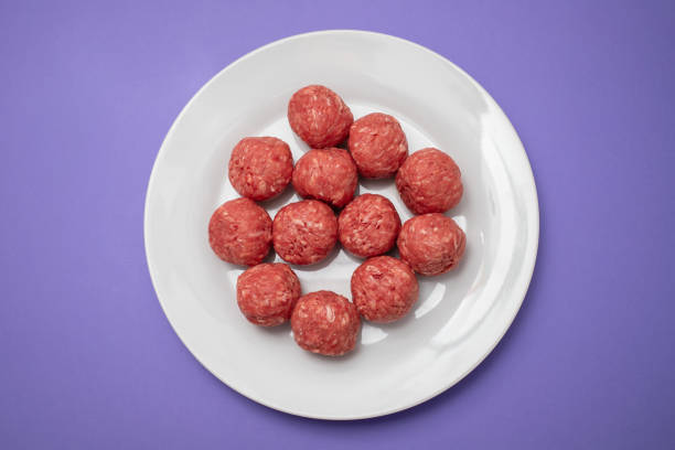 Top view of raw meat balls on white small plate