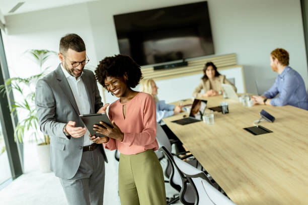 istock Joyful colleagues sharing a laugh over a tablet in a modern office meeting room 2148848864