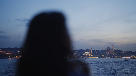 A portrait of a multiracial female solo traveler on a ferry looking at view in Istanbul Türkiye Turkey.
