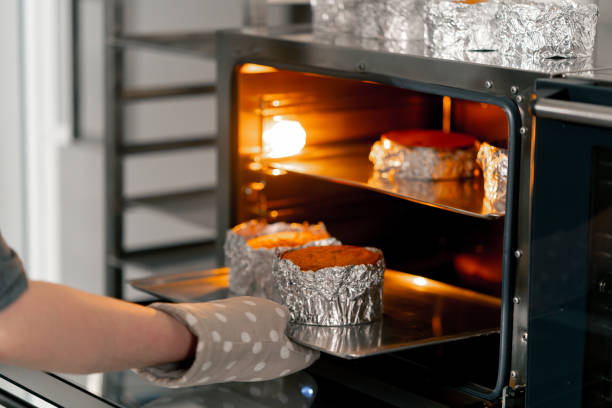 close up In a professional kitchen a baker takes out ready-made biscuits from the oven