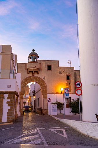 Rota lighthouse and Puerta del Mar arch door in Cadiz of Andalusia in Spain at sunset