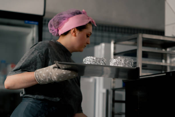istock in a professional kitchen a baker puts ready-made molds on a baking sheet into the oven 2148852590