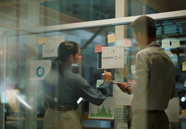 istock Window, team and board with analytics for planning in meeting, business people with tablet for graph analysis and agenda. Brainstorming, information and notes with research for project schedule 2148853412