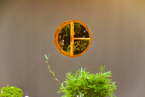 Circled wooden window above plants in front yard