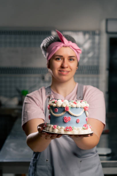 istock close-up in a professional kitchen a female baker stands with a finished cake in her hands she smiling 2148855907