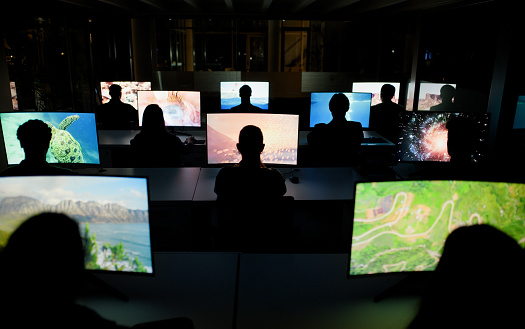 Employees, night and computer screens in centre, uploaders or production content creation on technology pc. Collaborative, workspace or team in office, back view and colleagues working together
