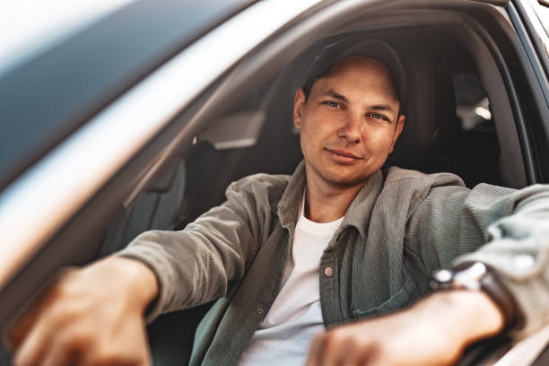 istock Young smiling man sitting in a car with open window 2148858868