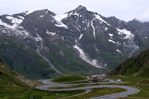 Grossglockner, Austria - July 24, 2023: Landscape photo of snow and glacier covered mountains and serpentine road in rainy weather