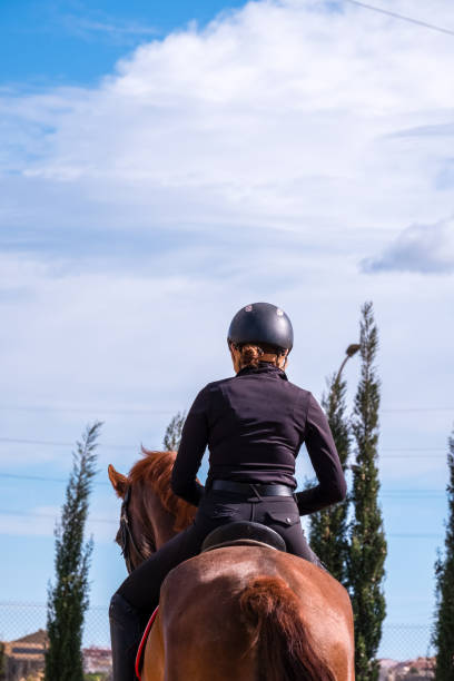 istock Young rider practicing horseback riding on a horse. Rear view. 2148861910
